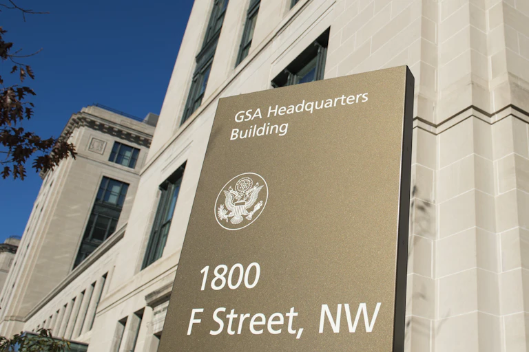 a metal sign in front of a large cement building