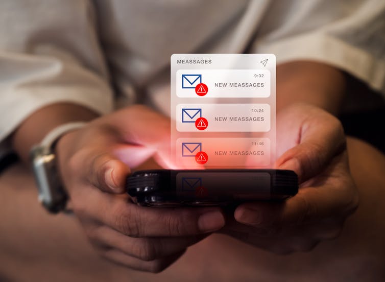 Close up of a pair of hands holding a cell phone with an interface displaying unread spam messages hovering over top