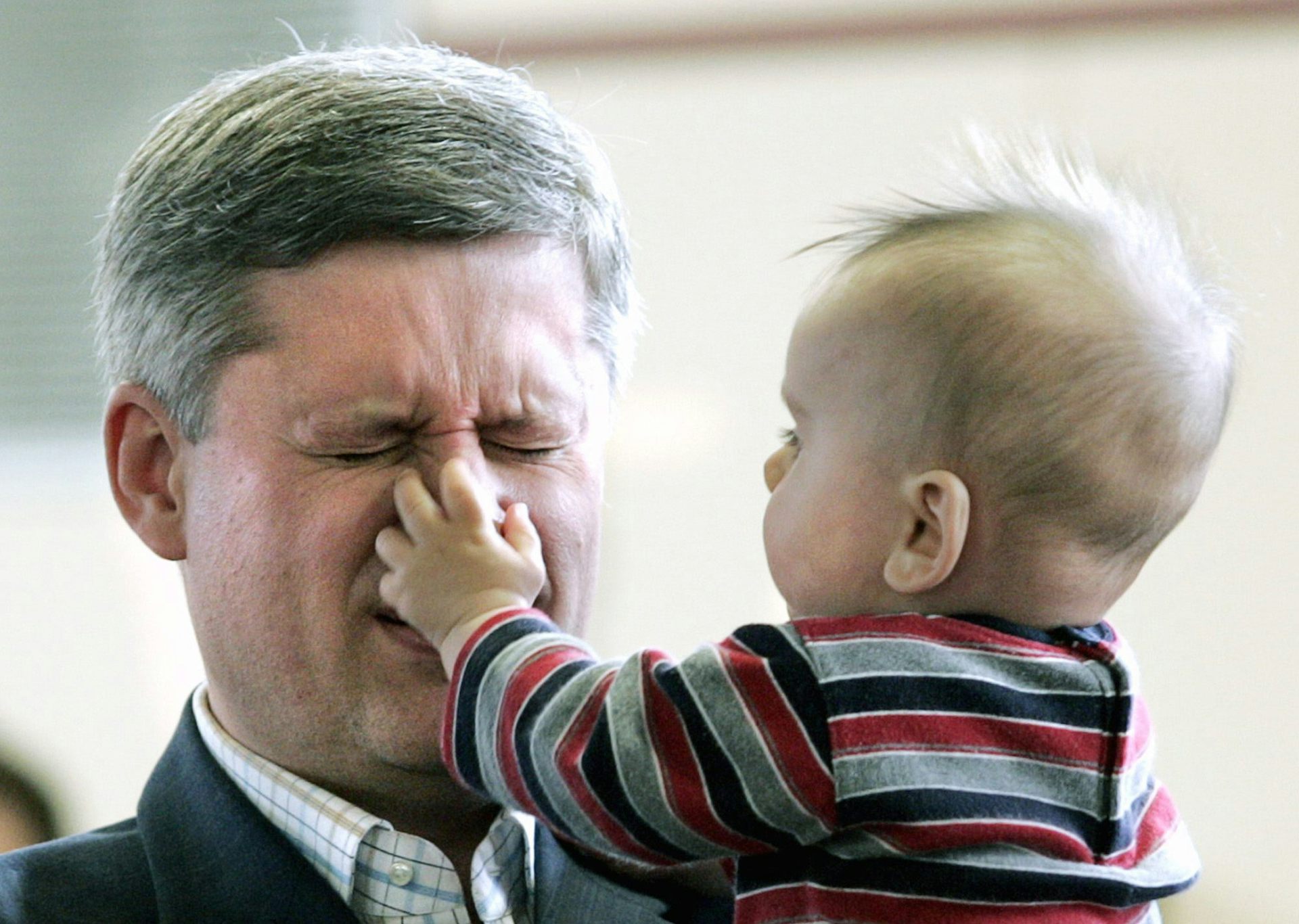 El bebé atrapa el pelo gris mueciente de la nariz del hombre.
