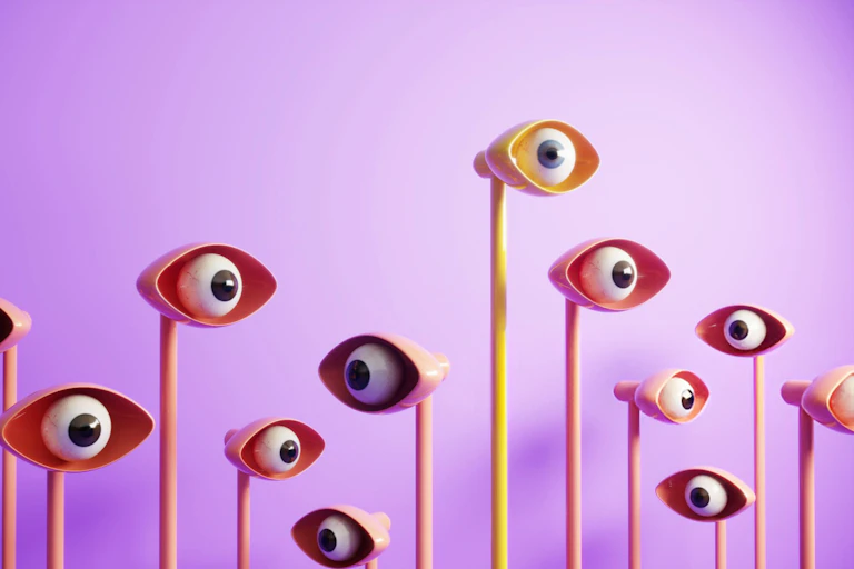 A crowd of artificial eyeballs on long poles against a bright purple background.