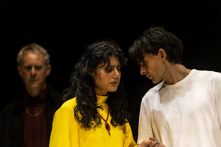 Production image: Henry talks into a woman's ear.