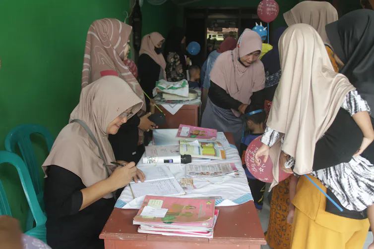 Kader kesehatan saat membantu layanan imunisasi polio anak.