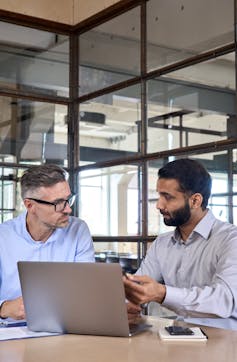 Two businessmen talking with a laptop