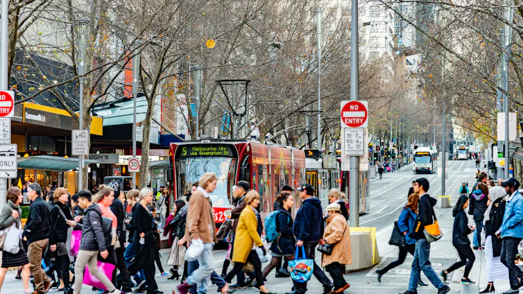 commuters walk near a tram in Melbourne