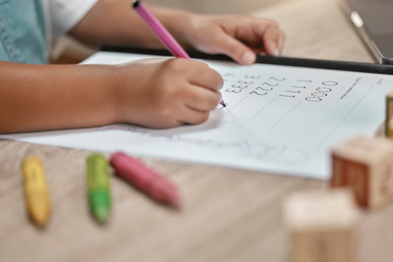 Child with pen and paper, crayons and blocks