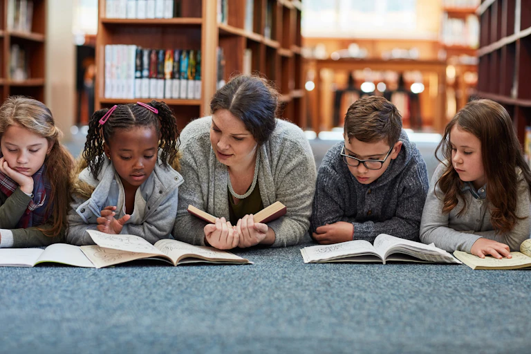 Children and teacher reading on floor in library