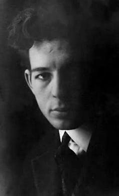 Fotografía en blanco y negro de un joven con camisa, corbata y suéter.