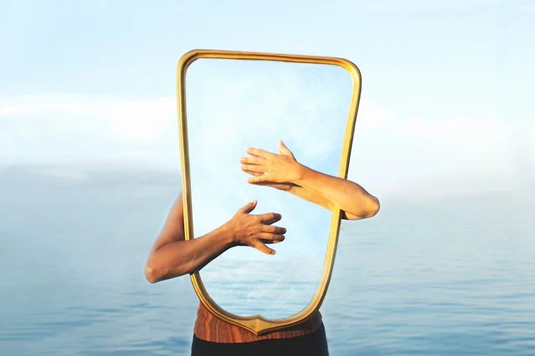 Man standing in the sea with arms wrapped around a mirror