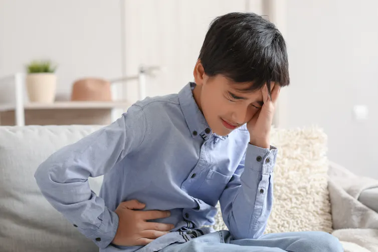 A child holds his side in agony.