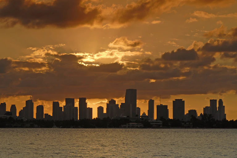 An orangish sunset over the Miami skyline which is dominated by tall towers