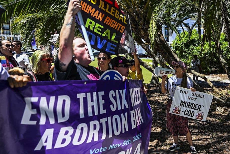 Protesters carry a large banner reading 'End the Six-Week Abortion Ban' as they march.