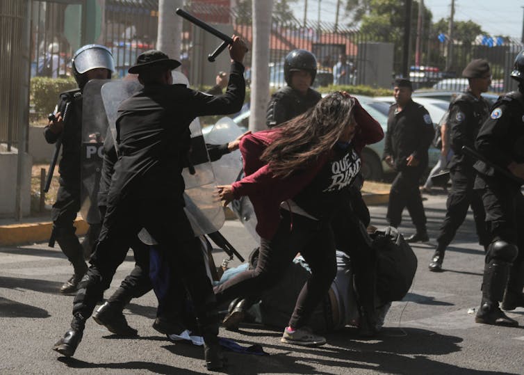 Security forces attacking a protester on the street.