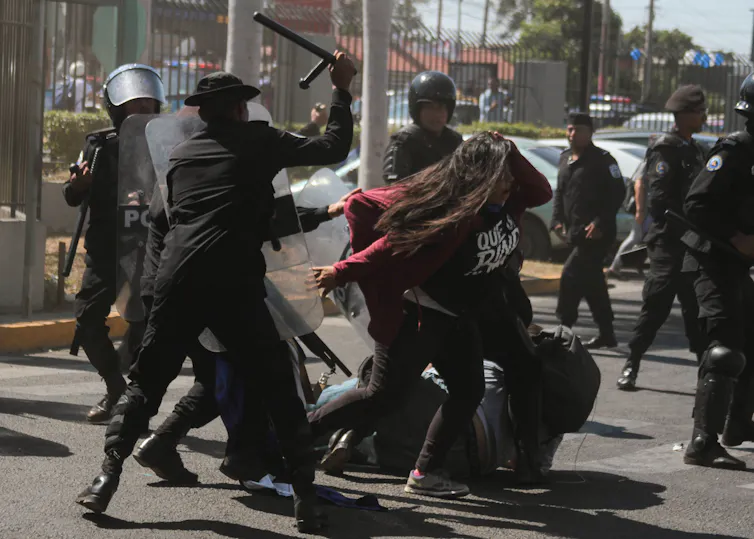 Security forces attacking a protester on the street.