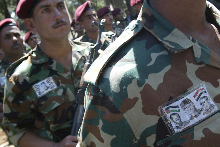 Soldiers wearing uniforms that have pictures of three men on a card on their chest.