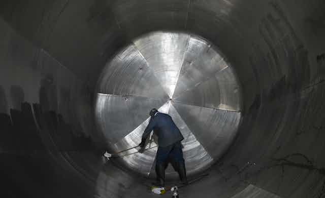 A man cleans the inside of a massive cylindrical steel tank