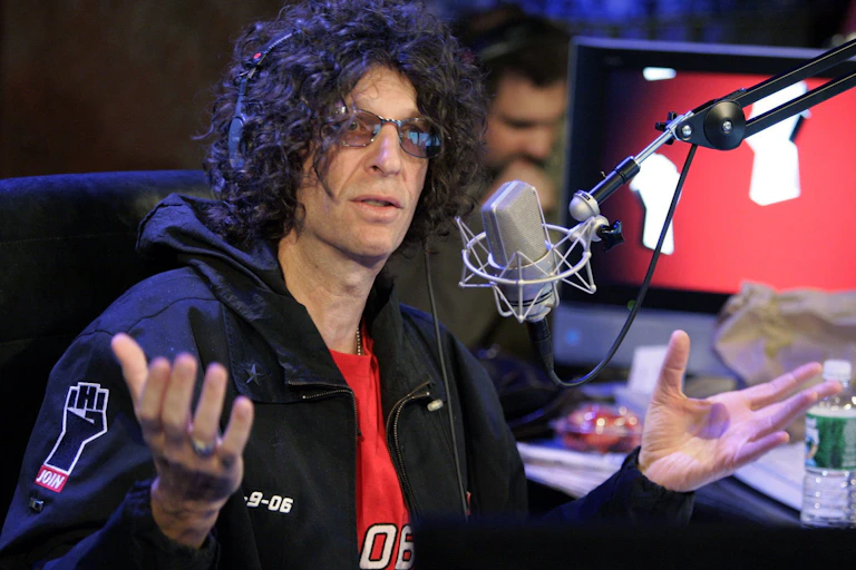 A man with curly hair and his palms held up.