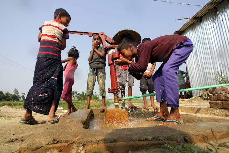 Children drinking water from a well.