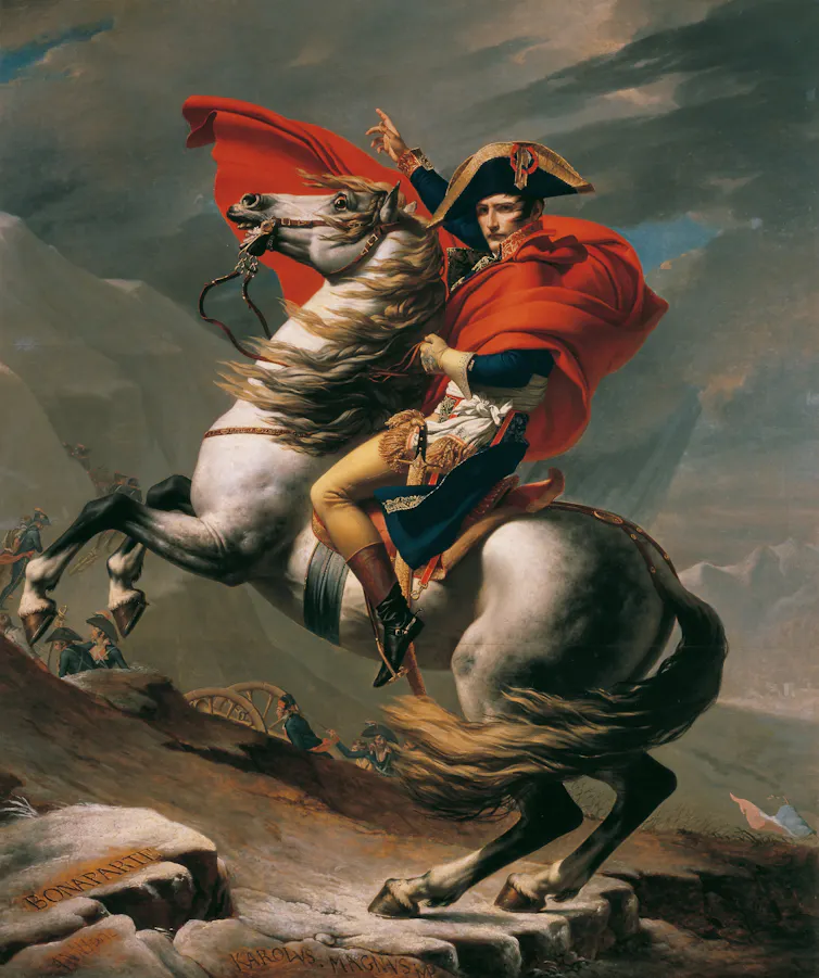 A man dressed in red, blue and gold royal garbs riding a white horse over mountains.