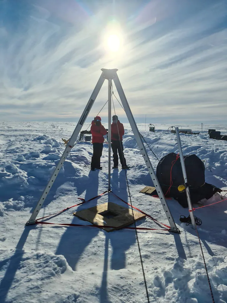 A drilling rig for penetrating the ice sheet in east Antarctica, with two scientists standing in the background