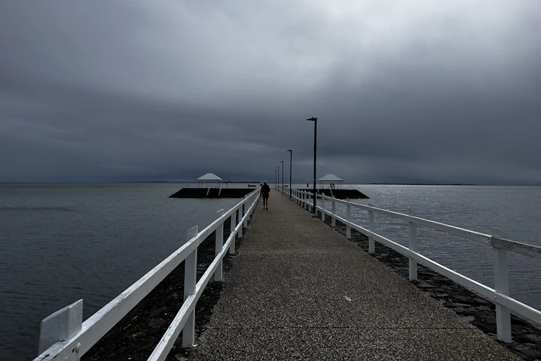 Cyclone Alfred approaching land, person walks along pier