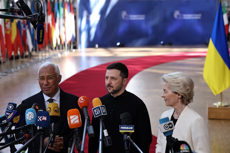 Three people stand behind media microphones