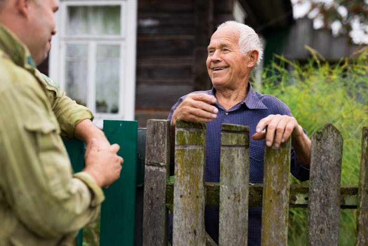 Old man chatting over the fence to neighbour