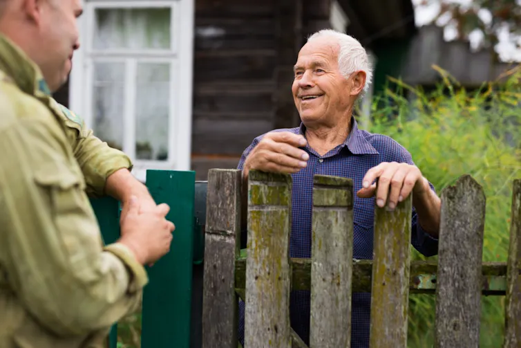 Old man chatting over the fence to neighbour
