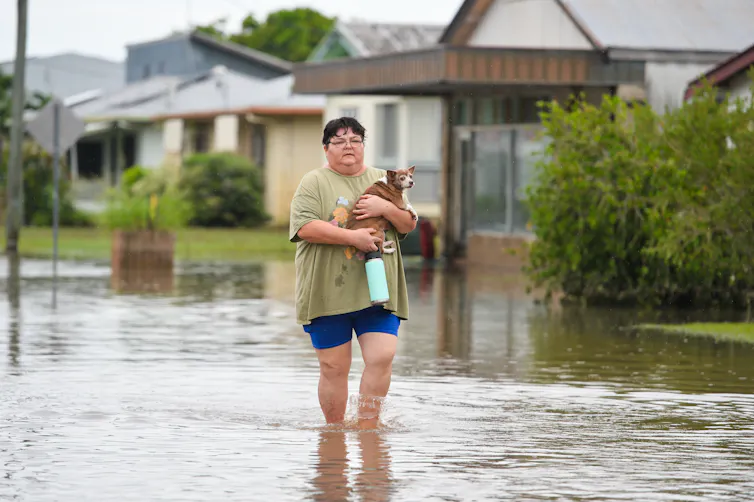 Kate Parison of Giru walks the flooded Lyons St with her dog, Tuesday, February 4, 2025
