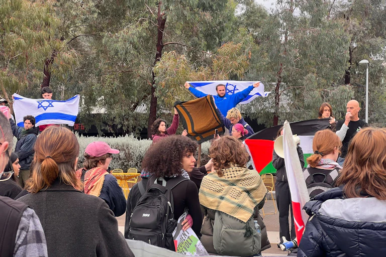 Protesters with both Israeli and Palestinian flags at a demonstration.