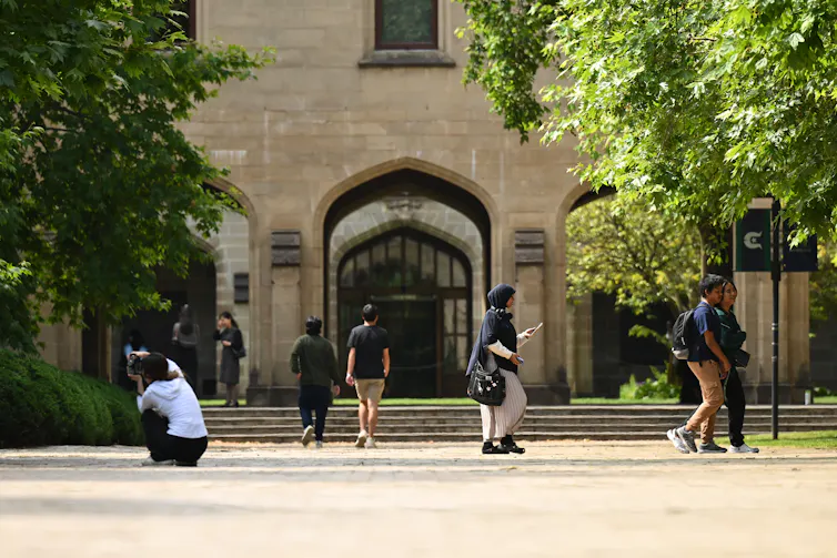 Students outside a sandstone building.