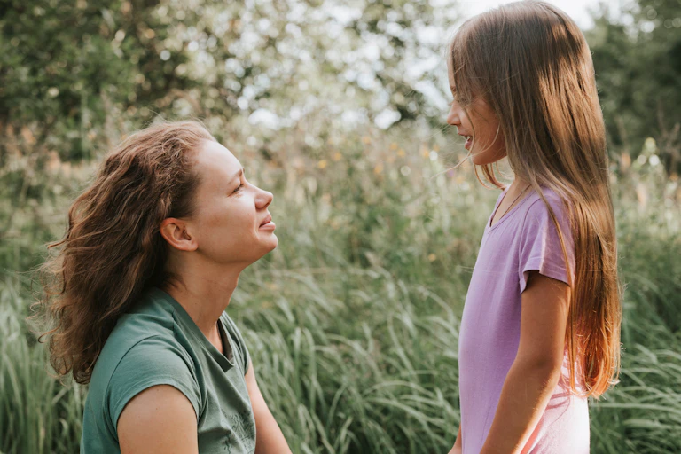 A woman with a small hearing aid in her ear speaks to a child.