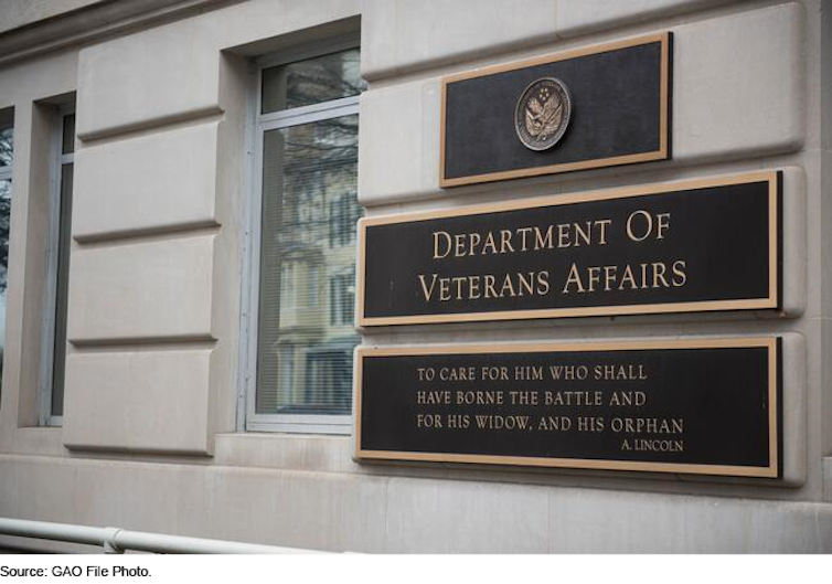 Signs on the side of a granite building.