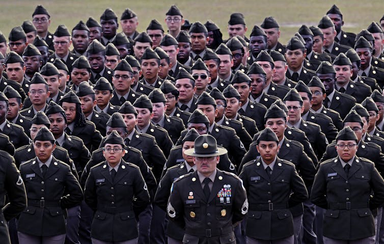 A group of people in military uniforms stand in formation.