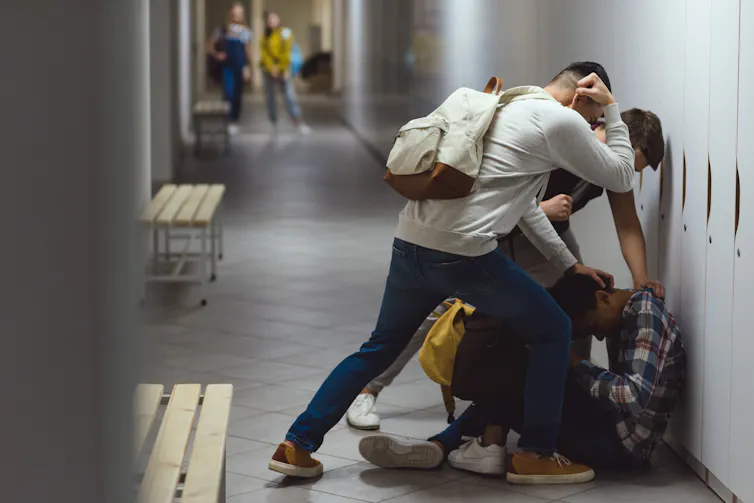 a teenager pushes another teen into a locker in a school
