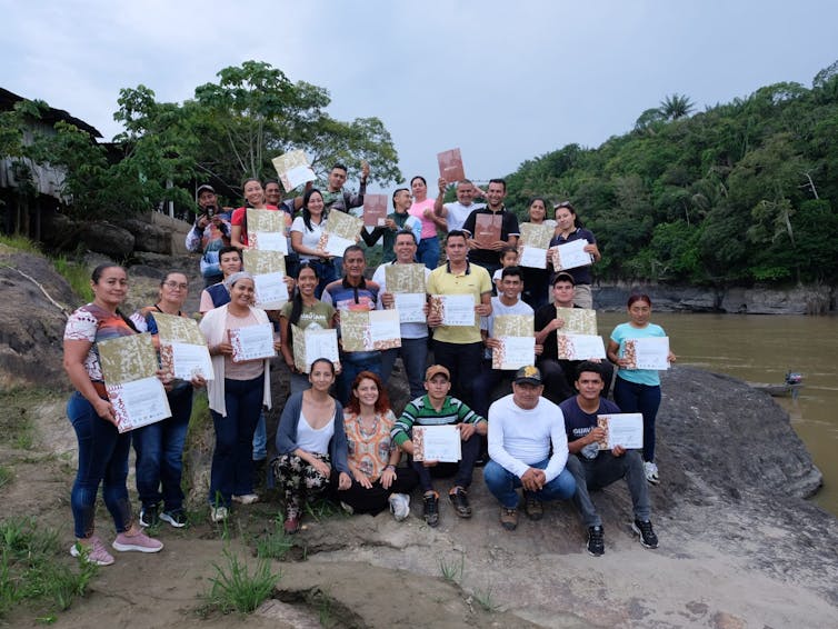 groups of 20 students holding paper certificates, standing outside