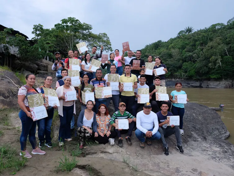 groups of 20 students holding paper certificates, standing outside