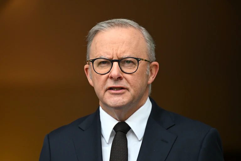 A man in a suit and glasses speaks