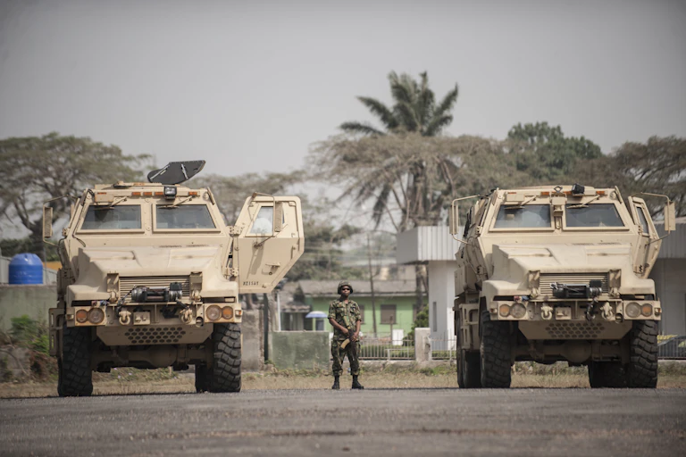 A soldier standing between two armoured vehicles