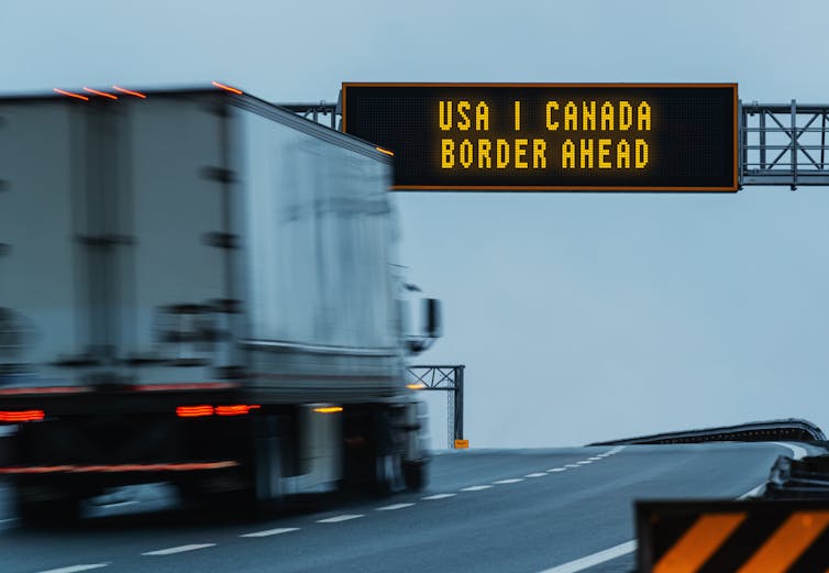 A truck driving past a sign that reads 'USA-Canada Border Ahead