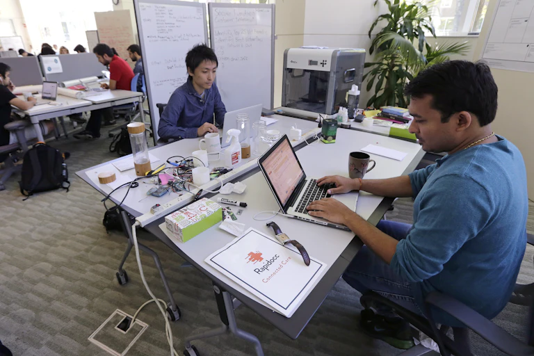 Two graduate students type on their laptop computers.