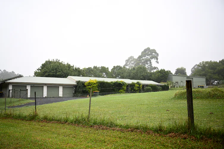 A green paddock with a house and shed