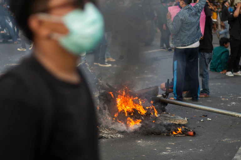 Orang berdiri di dekat api saat protes