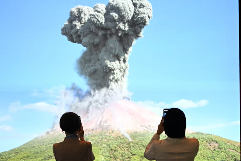 Two women watch a video of a volcanic eruption.