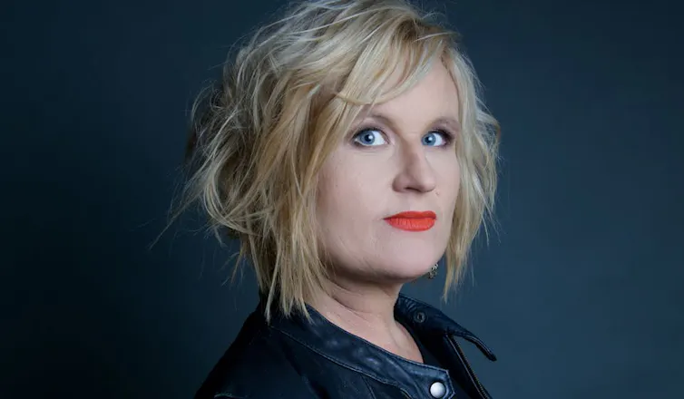 a blonde woman with red lipstick and tousled hair, in a leather jacket