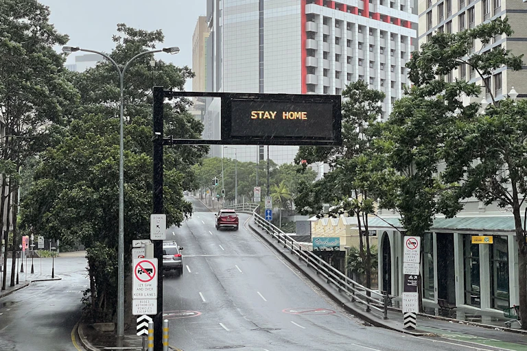 Photo of a rainy street with a large sign reading "STAY HOME"