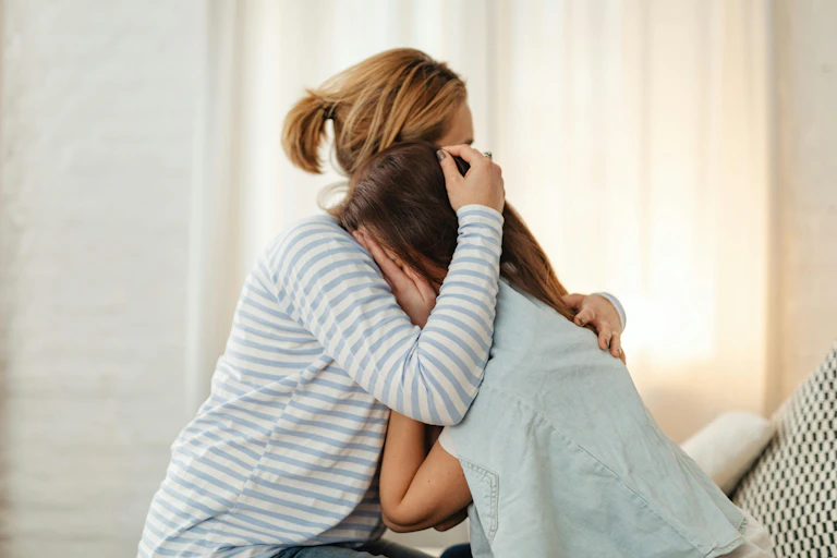 Mother holds her crying teen daughter.