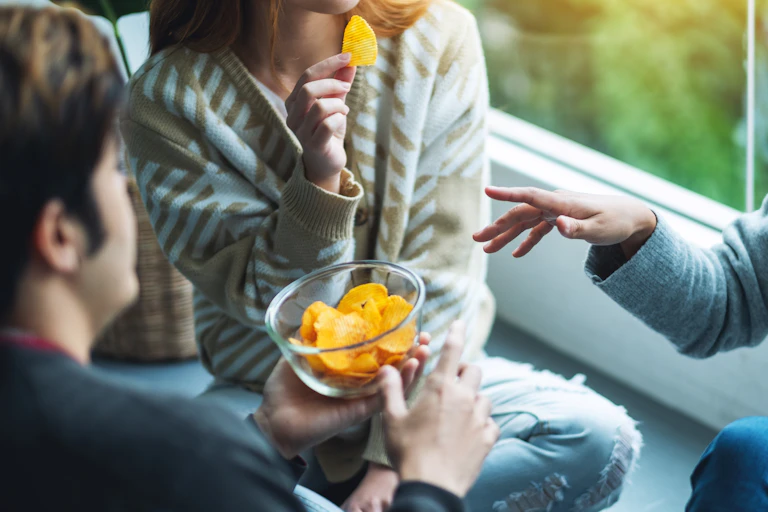 Friends sharing a bowl of crisps.