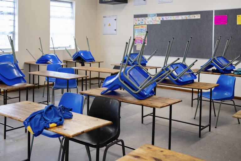 Chairs upturned on top of desks in a classroom