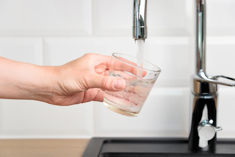 Person holding a glass under a tap.