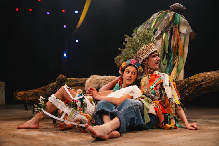 A man and a women lie on the floor in colourful clothing